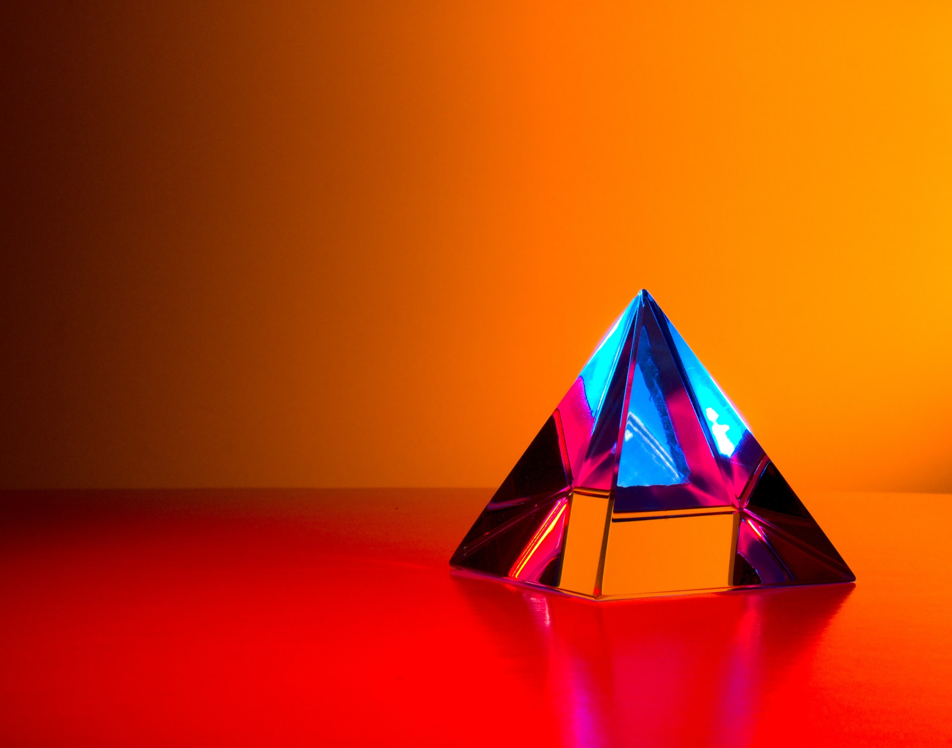 A colourful glass prism against a vibrant orange background