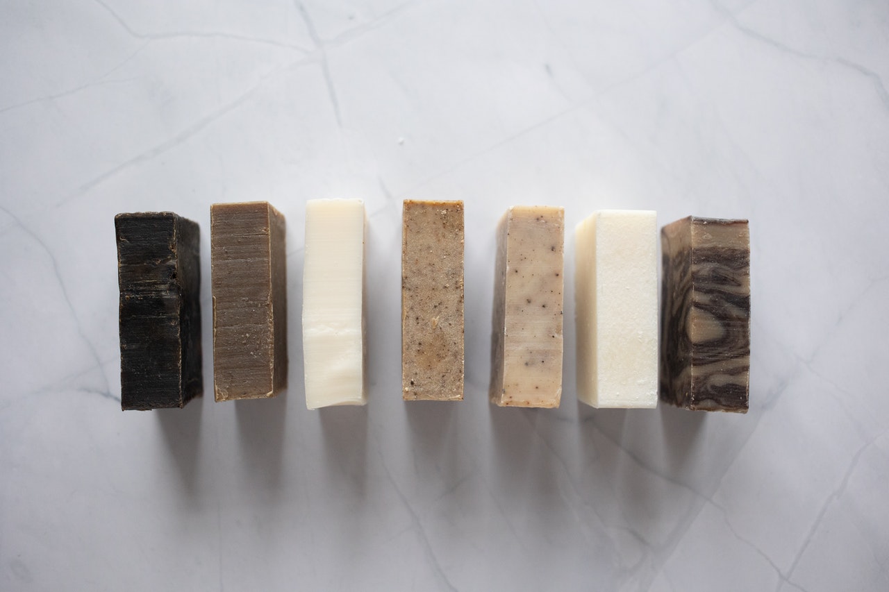 a collection of hand made bar soaps of various colours in a line