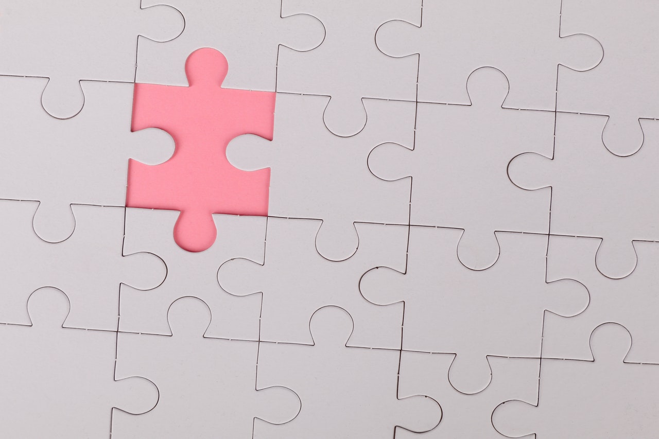 a white puzzle with a piece missing. The gap is pink.