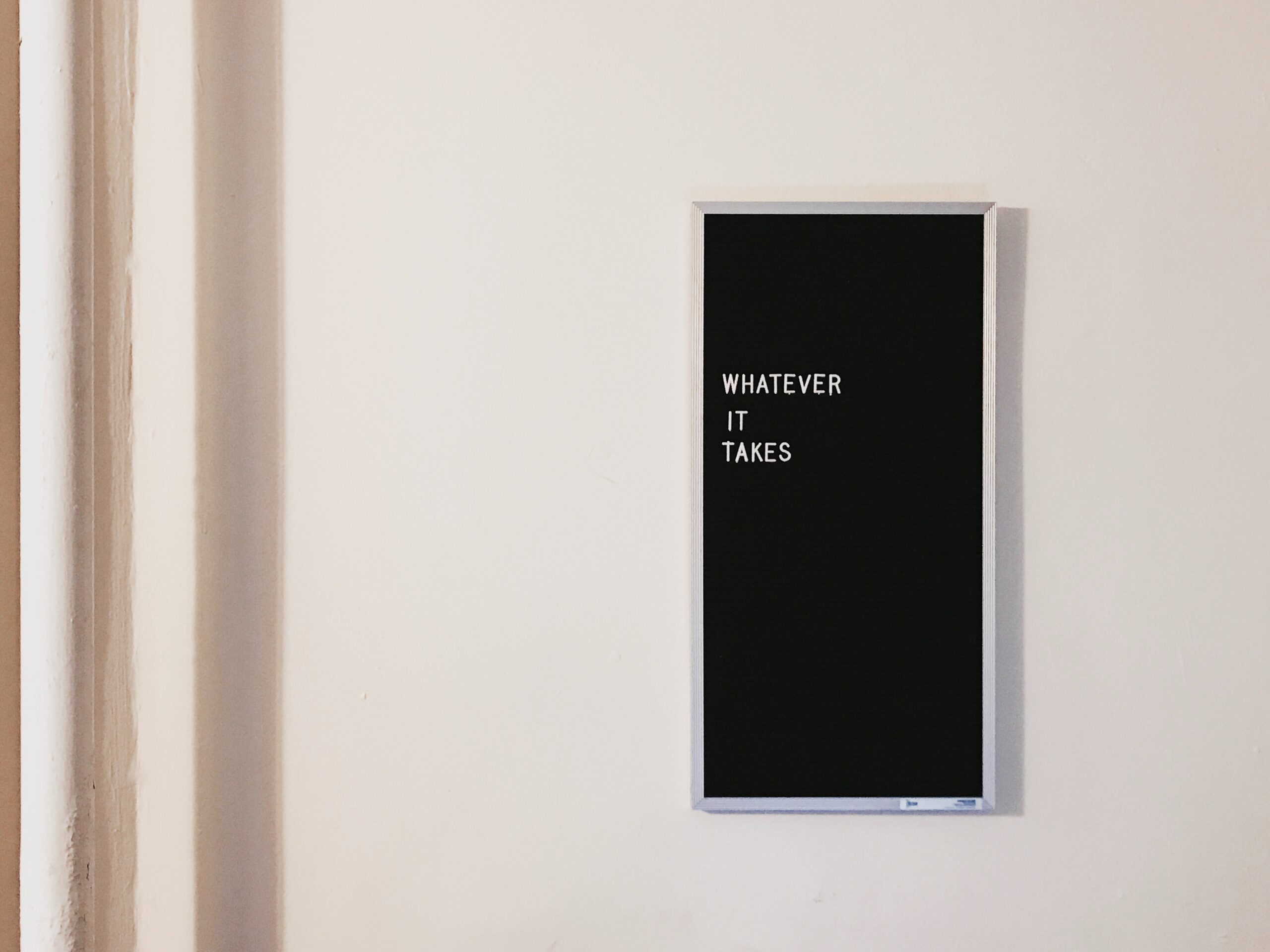 a blackboard on a wall with white lettering that says "whatever it takes"